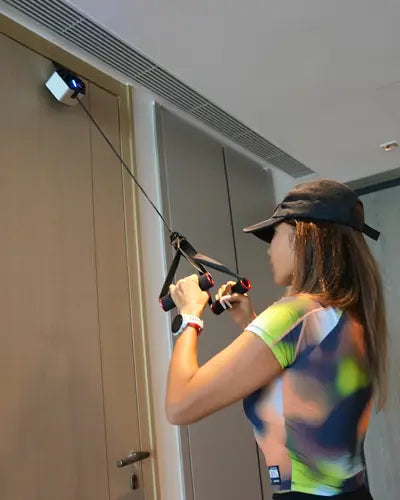 A woman training with Go-Tone anchored to the top of an apartment door